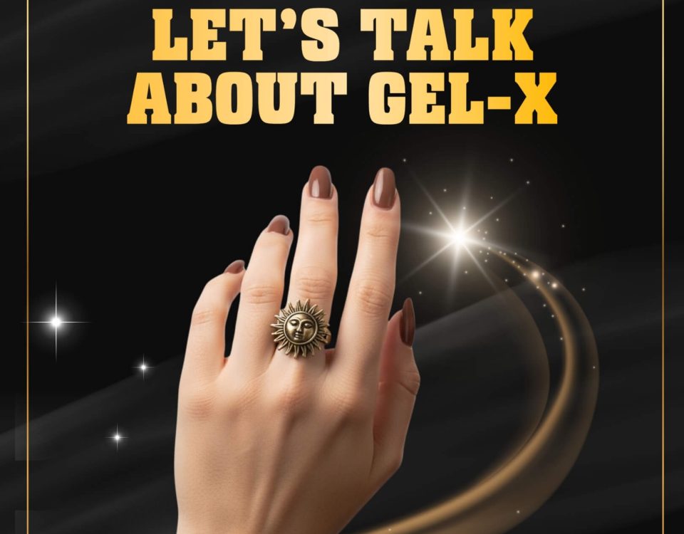 A hand with polished nails, sun-themed ring, and chain bracelet on a decorative background.